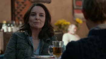 Movie still from “Whiskey Tango Foxtrot” (2016), directed by Glenn Ficarra – A woman sitting at a table with a plate of food; Close Up shot, Over the shoulder angle