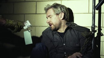 Movie still from “Whiskey Tango Foxtrot” (2016), directed by Glenn Ficarra – A man sitting in front of a brick wall with his mouth open; Close Up shot, Overhead angle