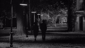 Movie still from “Who's Afraid of Virginia Woolf?” (1966), directed by Mike Nichols – Two people are standing on a path at night; Wide shot, High angle