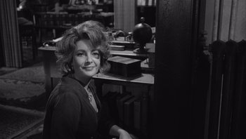 Movie still from “Who's Afraid of Virginia Woolf?” (1966), directed by Mike Nichols – A black and white photo of a woman sitting at a desk; Medium shot, Over the shoulder angle