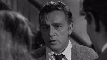 Movie still from “Who's Afraid of Virginia Woolf?” (1966), directed by Mike Nichols – Black and white photograph of a man in a suit; Close Up shot, Over the shoulder angle