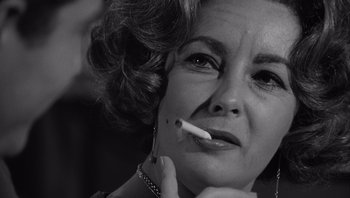 Movie still from “Who's Afraid of Virginia Woolf?” (1966), directed by Mike Nichols – An older woman smoking a cigarette in a black and white photo; Close Up shot, Low angle
