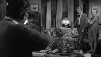 Movie still from “Who's Afraid of Virginia Woolf?” (1966), directed by Mike Nichols – A woman sitting on a couch in a living room; Medium shot, Over the shoulder angle