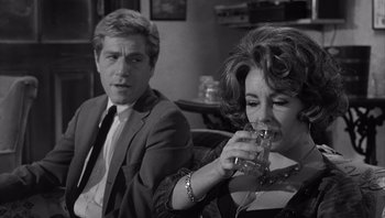 Movie still from “Who's Afraid of Virginia Woolf?” (1966), directed by Mike Nichols – A man and a woman sitting next to each other drinking water; Medium shot, Over the shoulder angle