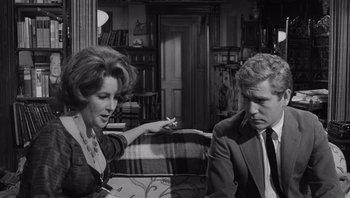 Movie still from “Who's Afraid of Virginia Woolf?” (1966), directed by Mike Nichols – An old photo of a man and a woman sitting on a couch; Medium shot, Over the shoulder angle