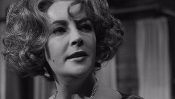Movie still from “Who's Afraid of Virginia Woolf?” (1966), directed by Mike Nichols – A person with curly hair wearing a necklace; Close Up shot, Over the shoulder angle