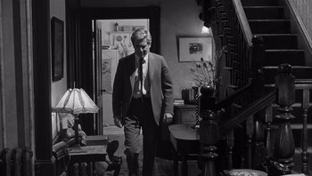 Movie still from “Who's Afraid of Virginia Woolf?” (1966), directed by Mike Nichols – A black and white photo of a man in a suit and tie; Medium shot, Low angle