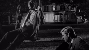 Movie still from “Who's Afraid of Virginia Woolf?” (1966), directed by Mike Nichols – A man and a woman swinging on a swing set at night; Medium shot, High angle
