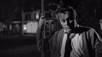 Movie still from “Who's Afraid of Virginia Woolf?” (1966), directed by Mike Nichols – A black and white photo of a man holding on to a rope; Medium shot, Low angle