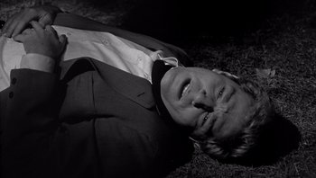 Movie still from “Who's Afraid of Virginia Woolf?” (1966), directed by Mike Nichols – A black and white photo of a man in a suit laying in the grass; Close Up shot, High angle