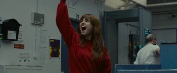 Movie still from “Wild Rose” (2018), directed by Tom Harper – A woman in a red hoodie is holding her arm up; Medium shot, Low angle