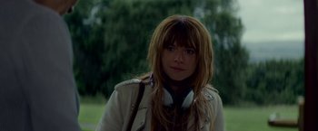 Movie still from “Wild Rose” (2018), directed by Tom Harper – A woman with long brown hair wearing a white jacket; Close Up shot, Over the shoulder angle