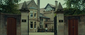 Movie still from “Wild Rose” (2018), directed by Tom Harper – A woman walking down a street in front of a building; Extreme Wide shot, Low angle
