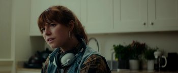 Movie still from “Wild Rose” (2018), directed by Tom Harper – A woman wearing a plaid shirt and headphones; Close Up shot, Over the shoulder angle