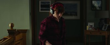 Movie still from “Wild Rose” (2018), directed by Tom Harper – A person wearing headphones and a plaid shirt; Medium shot, Over the shoulder angle