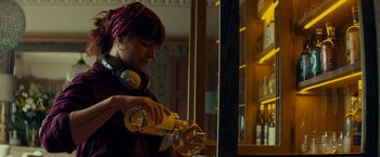 Movie still from “Wild Rose” (2018), directed by Tom Harper – A woman pouring a drink into a wine glass; Medium shot, Over the shoulder angle