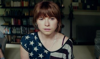 Movie still from “Wild Rose” (2018), directed by Tom Harper – A woman with a flag shirt on and bangs; Close Up shot, High angle