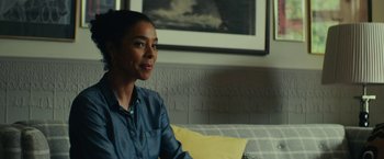 Movie still from “Wild Rose” (2018), directed by Tom Harper – A woman sitting on a couch in front of a picture; Close Up shot, Over the shoulder angle