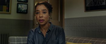 Movie still from “Wild Rose” (2018), directed by Tom Harper – A woman sitting in front of a door looking at the camera; Close Up shot, Over the shoulder angle