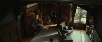 Movie still from “Wild Rose” (2018), directed by Tom Harper – A man is standing in a living room; Wide shot, High angle