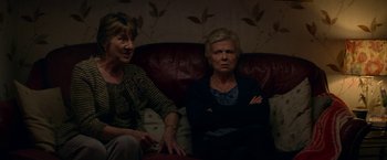 Movie still from “Wild Rose” (2018), directed by Tom Harper – Two older women sitting on a couch in a living room; Medium shot, High angle