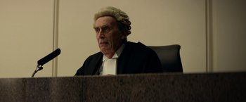 Movie still from “Wild Rose” (2018), directed by Tom Harper – An old man wearing a judges wig sitting in a courtroom; Medium shot, Low angle