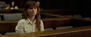 Movie still from “Wild Rose” (2018), directed by Tom Harper – A woman sitting in front of a row of wooden benches; Close Up shot, Over the shoulder angle