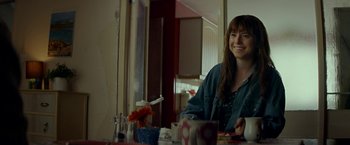 Movie still from “Wild Rose” (2018), directed by Tom Harper – A woman sitting at a table with a plate in front of her; Medium shot, Over the shoulder angle