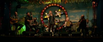 Movie still from “Wild Rose” (2018), directed by Tom Harper – A group of people on a stage with a microphone; Wide shot, Low angle