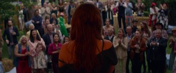 Movie still from “Wild Rose” (2018), directed by Tom Harper – A woman with long red hair standing in front of a group of people; Medium shot, Over the shoulder angle