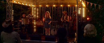 Movie still from “Wild Rose” (2018), directed by Tom Harper – A woman singing into a microphone on a stage; Wide shot, Over the shoulder angle