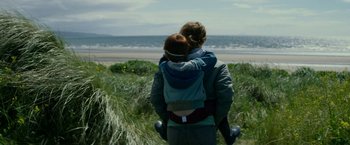 Movie still from “Wild Rose” (2018), directed by Tom Harper – A woman carrying a child in a baby carrier; Medium shot, Over the shoulder angle