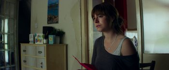 Movie still from “Wild Rose” (2018), directed by Tom Harper – A woman holding a red object in a room; Medium shot, Over the shoulder angle