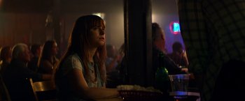 Movie still from “Wild Rose” (2018), directed by Tom Harper – A woman sitting at a table in front of a plate of food; Medium shot, Over the shoulder angle