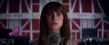 Movie still from “Wild Rose” (2018), directed by Tom Harper – A woman with a microphone in front of a brick wall; Close Up shot, Low angle