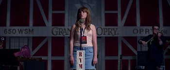 Movie still from “Wild Rose” (2018), directed by Tom Harper – A woman standing in front of a microphone on a stage; Medium shot, Low angle