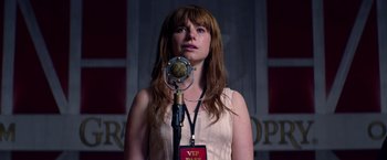 Movie still from “Wild Rose” (2018), directed by Tom Harper – A woman standing in front of a microphone; Close Up shot, Over the shoulder angle