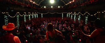 Movie still from “Wild Rose” (2018), directed by Tom Harper – A woman playing a guitar in front of an audience; Extreme Wide shot, High angle