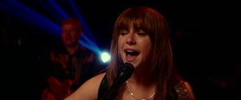 Movie still from “Wild Rose” (2018), directed by Tom Harper – A woman singing into a microphone in front of a crowd; Close Up shot, Over the shoulder angle