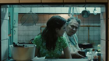 Movie still from “Wild Tales” (2014), directed by Damián Szifron – A woman and an older woman sitting at a table in a kitchen; Medium shot, Over the shoulder angle
