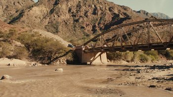 Movie still from “Wild Tales” (2014), directed by Damián Szifron – A bridge over a body of water near a mountain range; Extreme Wide shot, High angle