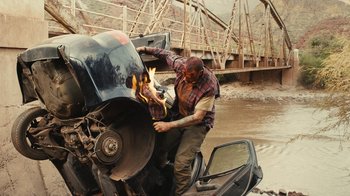 Movie still from “Wild Tales” (2014), directed by Damián Szifron – A man working on a motorcycle that is on fire; Wide shot, High angle