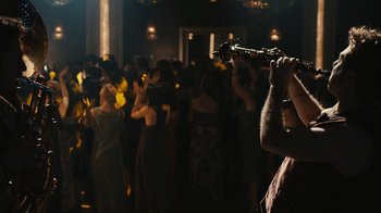 Movie still from “Wild Tales” (2014), directed by Damián Szifron – A man holding a saxophone in a room full of people; Medium shot, Over the shoulder angle