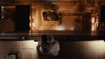 Movie still from “Wild Tales” (2014), directed by Damián Szifron – A person sitting on the ground in front of a window; Extreme Wide shot, Overhead angle