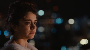 Movie still from “Wild Tales” (2014), directed by Damián Szifron – A person looking sad with lights in the background; Close Up shot, Over the shoulder angle