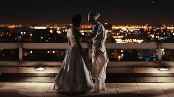 Two people standing next to each other on a balcony at night