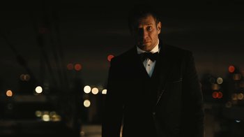 Movie still from “Wild Tales” (2014), directed by Damián Szifron – A man in a suit and bow tie standing in the dark; Medium shot, Low angle