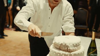 Movie still from “Wild Tales” (2014), directed by Damián Szifron – A man in a white shirt cutting a cake; Medium shot, Over the shoulder angle