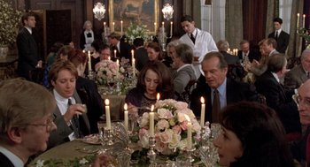Movie still from “Wolf” (1994), directed by Mike Nichols – A group of people sitting around a table with candles on top of it; Wide shot, Over the shoulder angle