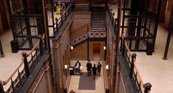 Movie still from “Wolf” (1994), directed by Mike Nichols – A group of people walking down a hall way; Extreme Wide shot, Overhead angle